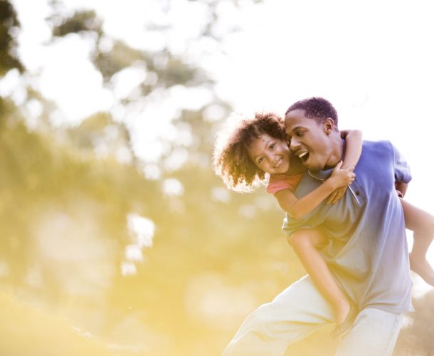 Playful African American father and daughter having fun in nature.